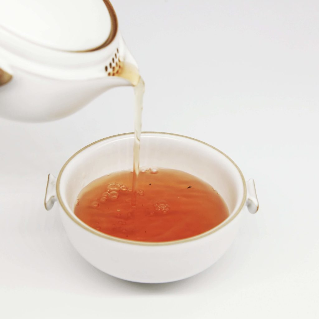 tea being poured from a kettle into a teacup 